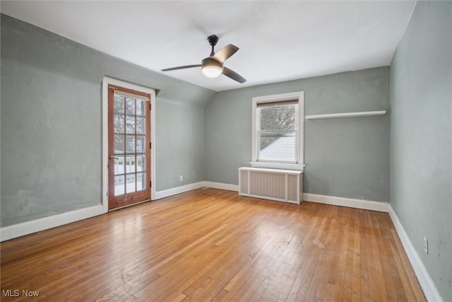 unfurnished room with vaulted ceiling, radiator heating unit, ceiling fan, and light hardwood / wood-style flooring