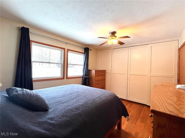 bedroom with wood-type flooring, a textured ceiling, and ceiling fan