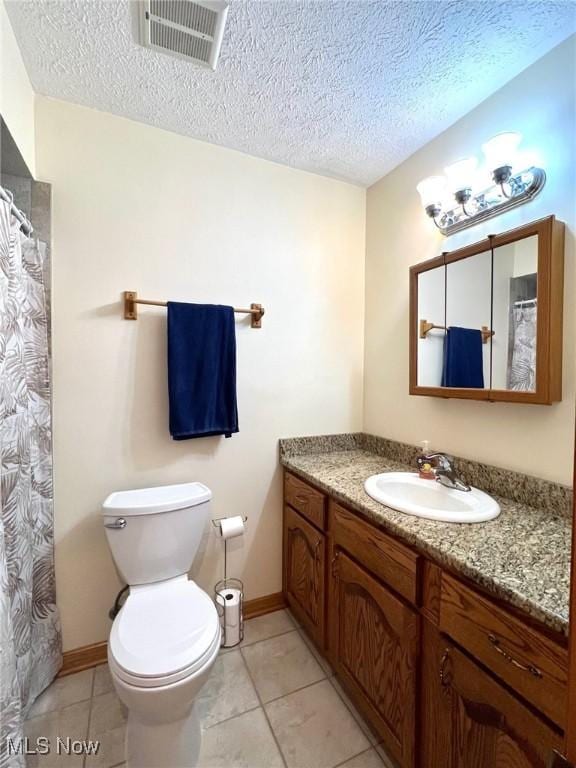 bathroom with tile patterned flooring, vanity, toilet, and a textured ceiling