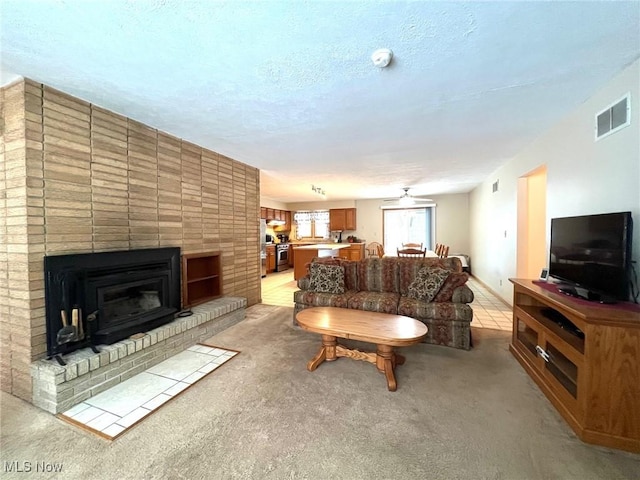 carpeted living room featuring a brick fireplace and a textured ceiling