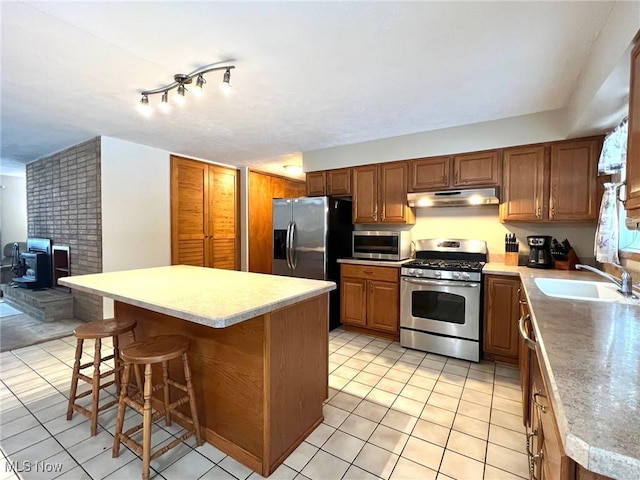 kitchen with stainless steel appliances, a kitchen island, sink, and a kitchen bar