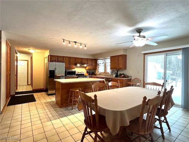 dining room featuring ceiling fan, sink, light tile patterned floors, and a textured ceiling