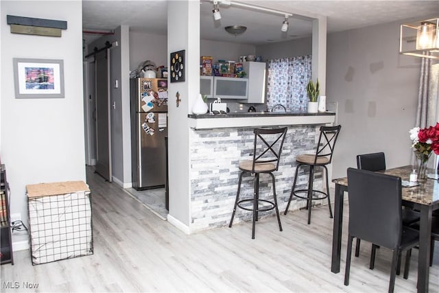 kitchen featuring stainless steel fridge, a barn door, and light hardwood / wood-style floors