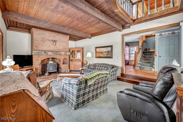 living room featuring beamed ceiling, carpet floors, a wood stove, and wooden ceiling