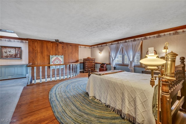 bedroom featuring hardwood / wood-style flooring, crown molding, and a textured ceiling