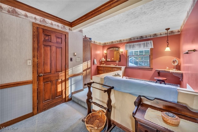 kitchen with decorative light fixtures, ornamental molding, light colored carpet, and a textured ceiling