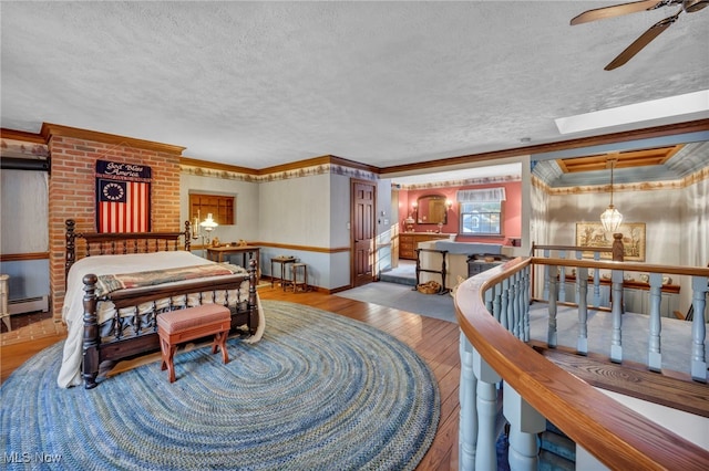 bedroom featuring a baseboard heating unit, crown molding, light hardwood / wood-style flooring, and a textured ceiling