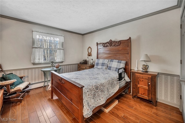 bedroom with baseboard heating, ornamental molding, a textured ceiling, and light wood-type flooring