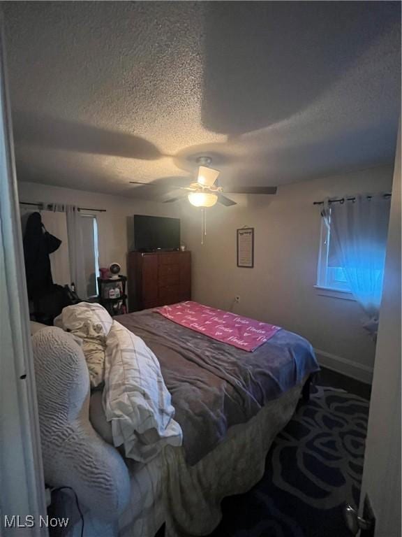 bedroom with ceiling fan and a textured ceiling