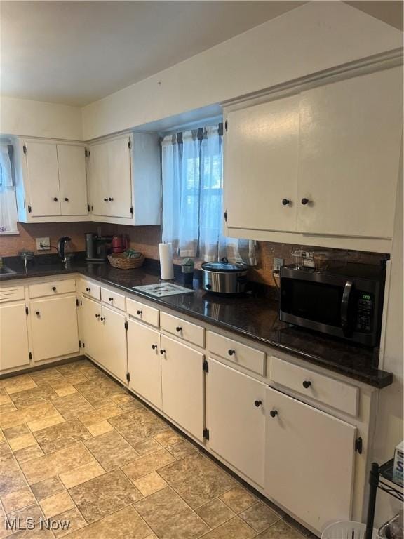 kitchen featuring dark stone countertops, decorative backsplash, and white cabinets