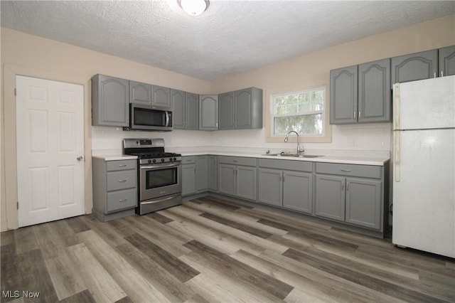 kitchen with gray cabinetry, sink, dark wood-type flooring, and appliances with stainless steel finishes