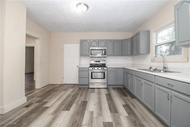 kitchen featuring gray cabinets, dark hardwood / wood-style floors, sink, stainless steel appliances, and a textured ceiling