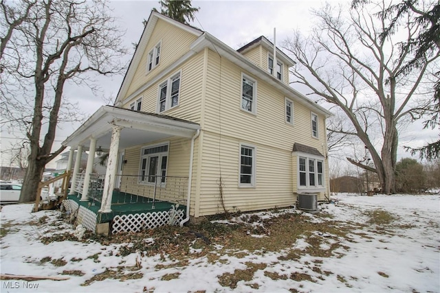 view of snow covered exterior featuring central AC and a porch