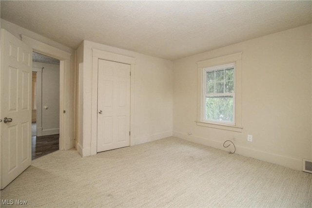 unfurnished bedroom featuring light colored carpet and a textured ceiling