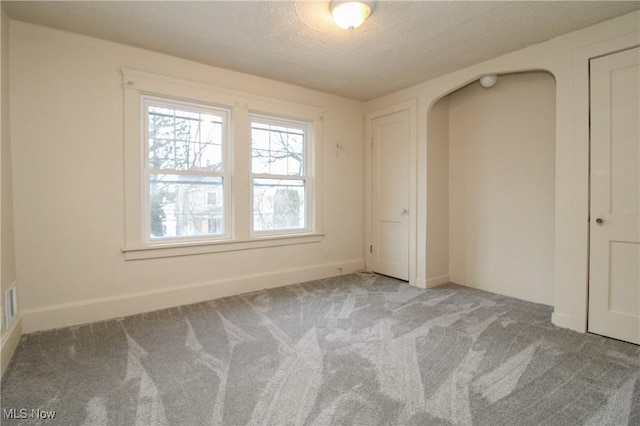 unfurnished bedroom with light colored carpet and a textured ceiling