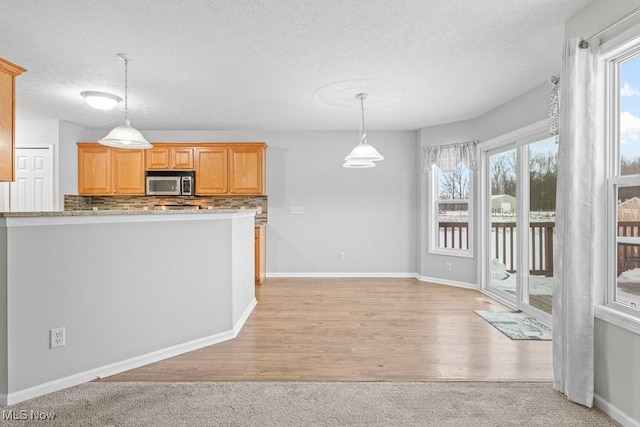 kitchen featuring tasteful backsplash, a wealth of natural light, a textured ceiling, and light brown cabinets