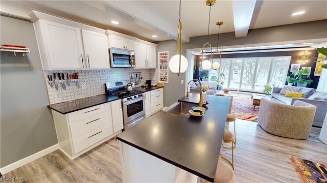 kitchen featuring pendant lighting, stainless steel appliances, a kitchen breakfast bar, white cabinets, and beamed ceiling