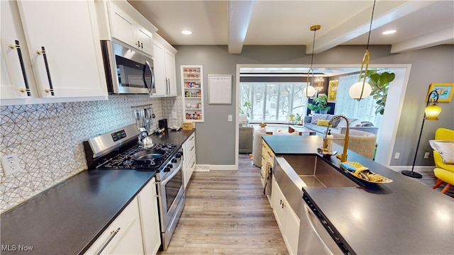 kitchen with sink, decorative light fixtures, stainless steel appliances, beam ceiling, and white cabinets