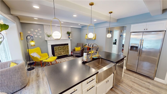 kitchen with light hardwood / wood-style flooring, stainless steel appliances, white cabinets, decorative light fixtures, and beamed ceiling