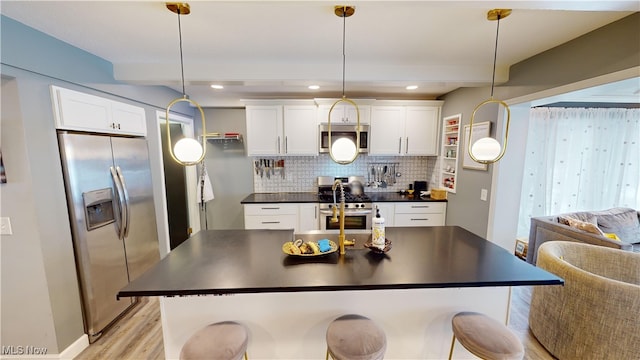 kitchen featuring white cabinetry, a breakfast bar area, tasteful backsplash, and appliances with stainless steel finishes