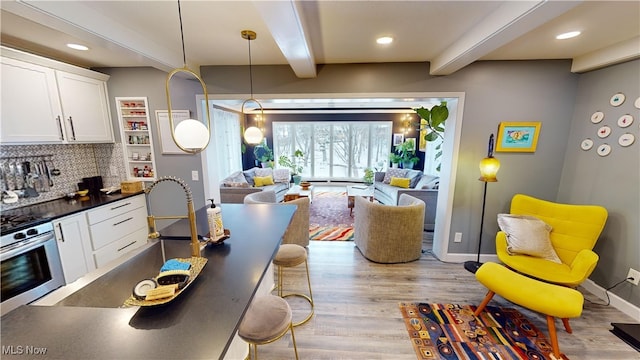 interior space with white cabinetry, sink, light hardwood / wood-style flooring, and beamed ceiling