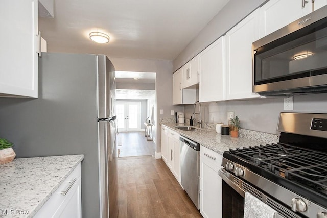 kitchen featuring sink, stainless steel appliances, light stone countertops, hardwood / wood-style floors, and white cabinets