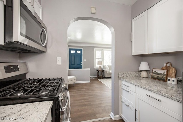 kitchen featuring light stone counters, stainless steel appliances, dark wood-type flooring, and white cabinets