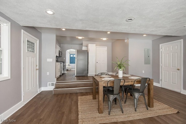 dining area featuring dark hardwood / wood-style flooring, electric panel, and a textured ceiling