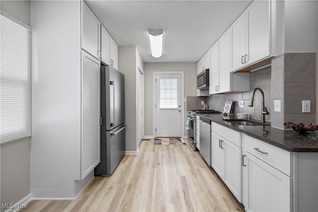 kitchen featuring dark stone countertops, stainless steel appliances, sink, and white cabinets