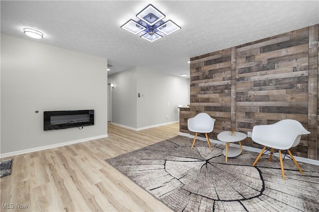 living area featuring heating unit, light hardwood / wood-style floors, a textured ceiling, and wood walls