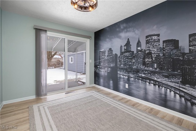 spare room featuring hardwood / wood-style flooring and a textured ceiling