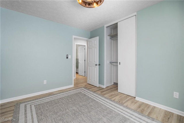 unfurnished bedroom featuring a closet, a textured ceiling, and light hardwood / wood-style flooring