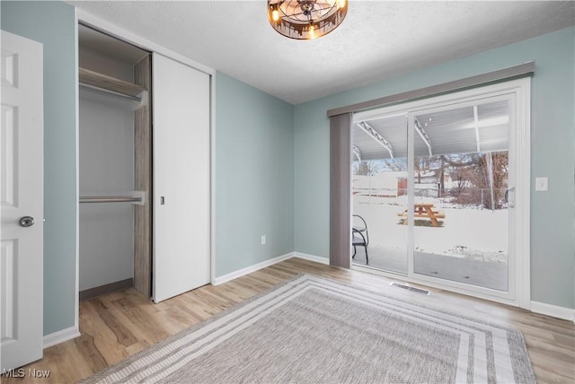 unfurnished bedroom with light hardwood / wood-style flooring, a closet, and a textured ceiling