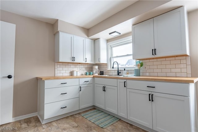 kitchen with butcher block counters, white cabinetry, and decorative backsplash