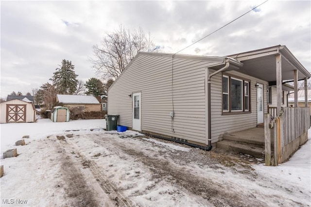 view of snowy exterior with a shed