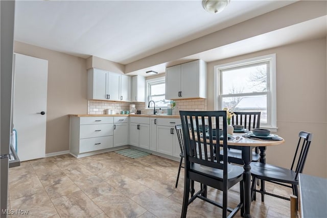 kitchen featuring sink, decorative backsplash, and white cabinets