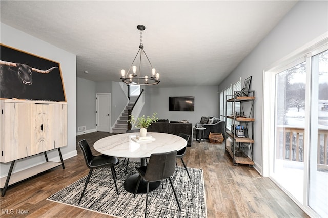 dining space with hardwood / wood-style flooring and an inviting chandelier