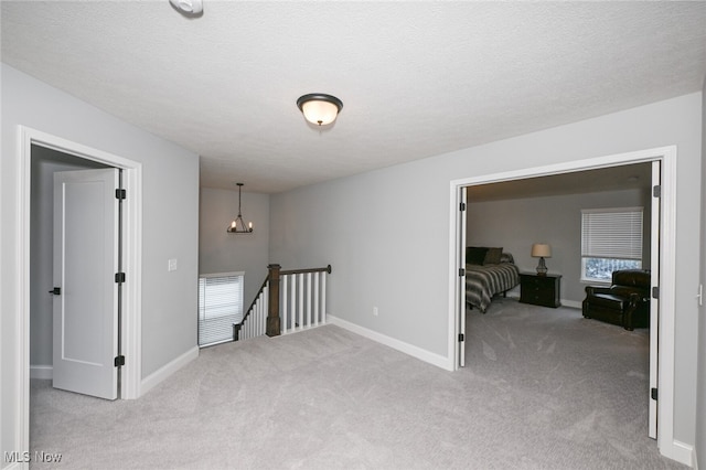 hall with light carpet and a textured ceiling