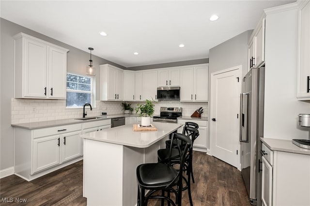 kitchen featuring a kitchen island, decorative light fixtures, sink, white cabinets, and stainless steel appliances