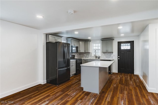 kitchen featuring dark hardwood / wood-style floors, gray cabinets, a kitchen island, decorative backsplash, and black appliances