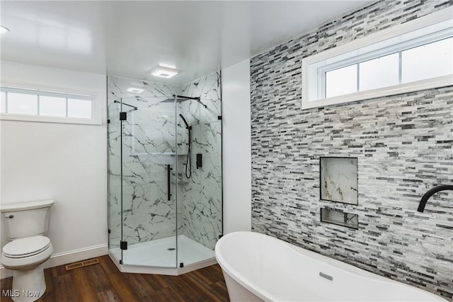 bathroom featuring shower with separate bathtub, plenty of natural light, hardwood / wood-style floors, and toilet