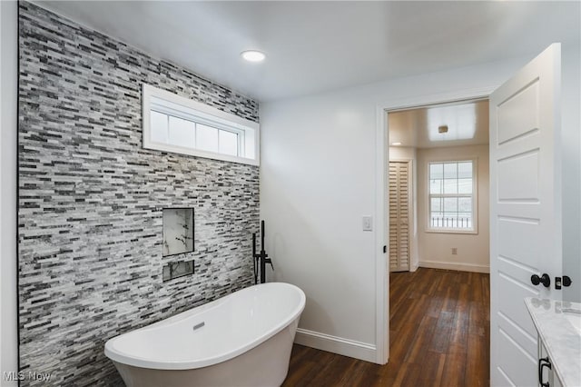 bathroom featuring vanity, a bath, hardwood / wood-style flooring, and a healthy amount of sunlight