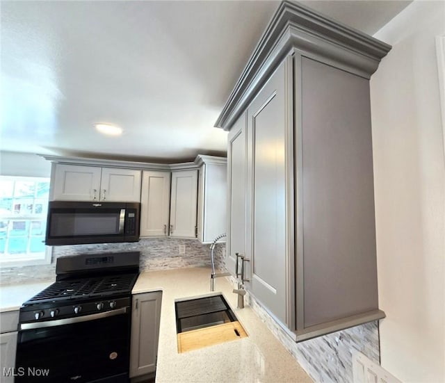 kitchen featuring gray cabinetry, sink, backsplash, and black gas stove