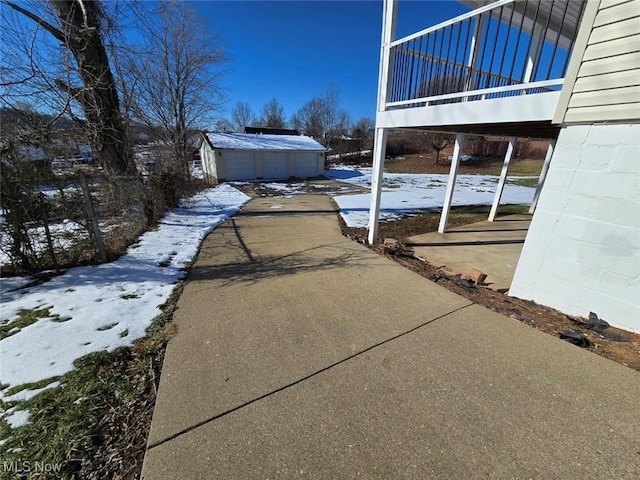 view of snowy exterior featuring a garage, an outbuilding, and a balcony