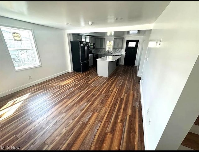 kitchen featuring tasteful backsplash, gray cabinets, dark hardwood / wood-style flooring, and black appliances