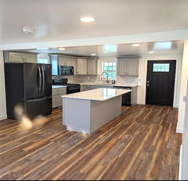 kitchen with gray cabinets, a kitchen island, dark hardwood / wood-style flooring, and black appliances