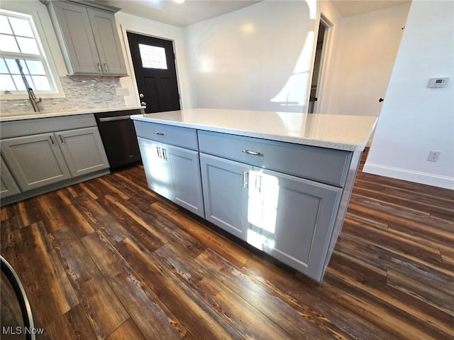 kitchen featuring dark hardwood / wood-style floors, gray cabinets, dishwasher, and a kitchen island