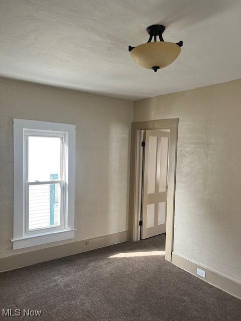 unfurnished room featuring dark colored carpet