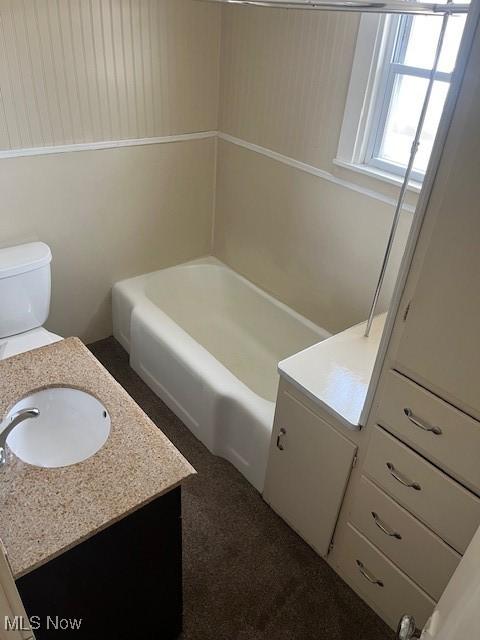 bathroom with vanity, toilet, and a tub