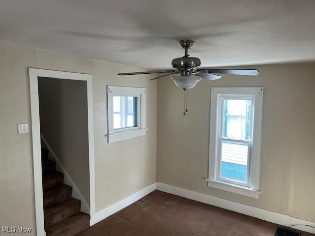 carpeted spare room featuring ceiling fan